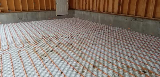 Radiant floor heating system with orange and white tubing on a concrete floor