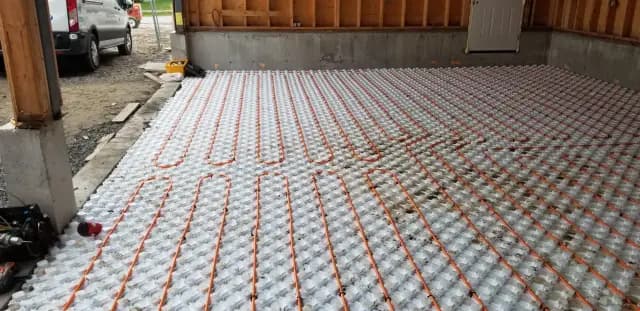 A close-up view of the radiant floor heating system being installed on a concrete floor with insulation underneath.