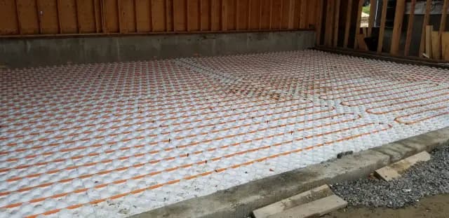 Radiant floor heating system installation with orange and white tubing on a concrete slab