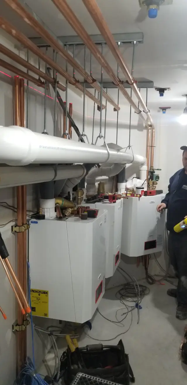 Copper pipes are neatly arranged above white insulation, with tools and equipment scattered around