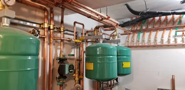Copper piping with green expansion tank, valves, and fittings