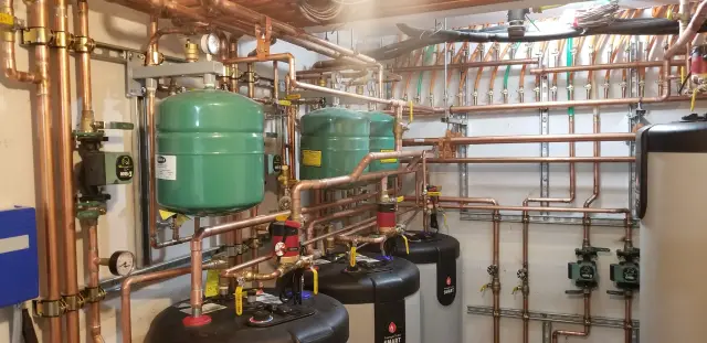 Copper pipes with green expansion tanks installed in a utility room