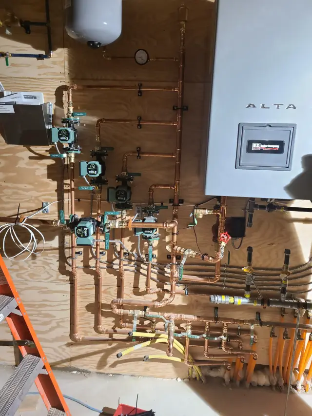 A close-up view of the Alta water heater, showcasing its gray exterior and digital display, mounted on a