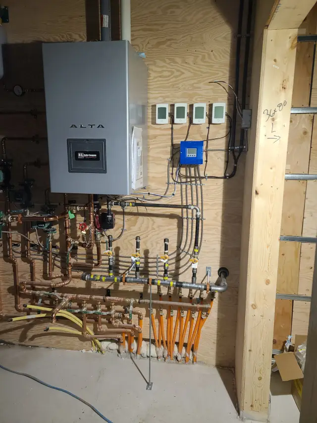 A large gray furnace with the brand 'Alta' clearly visible is part of a heating system with various