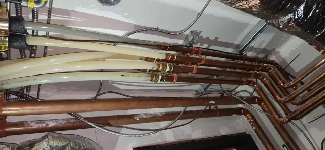 Copper pipes with white insulation, installed on wall