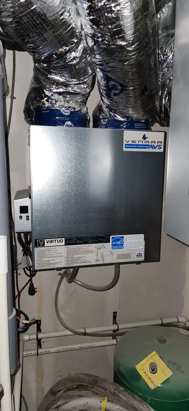 Outdoor Gree heat pump with a silver casing and a blue logo, installed on a concrete surface with