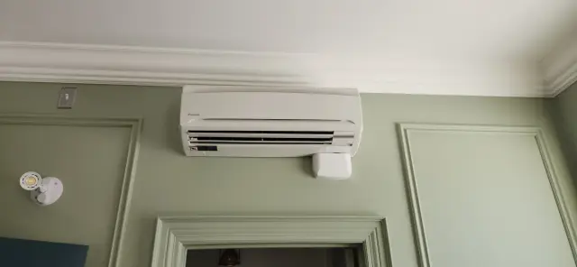 Air conditioning unit mounted on a wall with a white casing