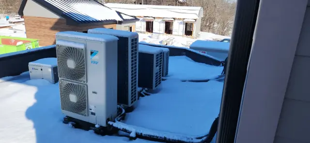Outdoor heat pump installed on roof with snow around