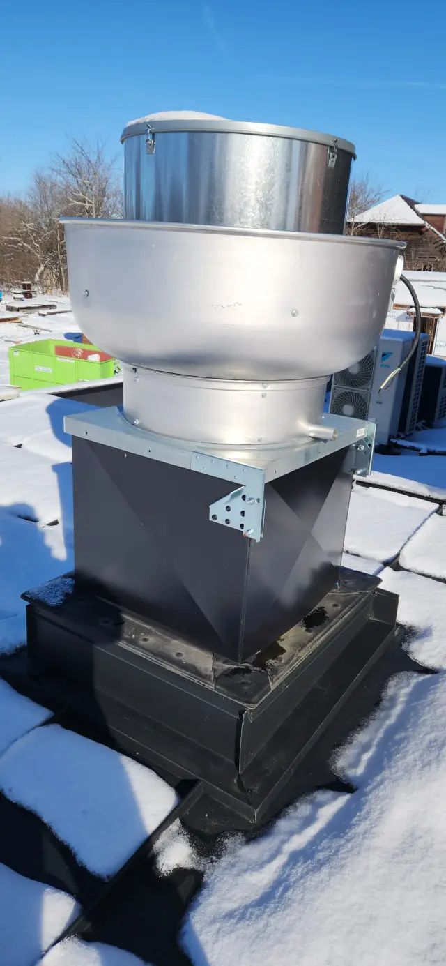 A close-up of an HVAC unit on a snowy roof, highlighting the metallic structure and the cold environment, with no visible brand or model details.