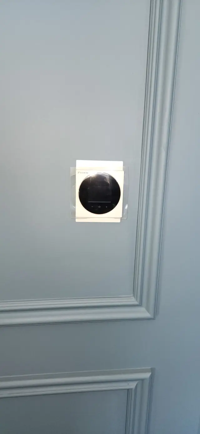 A technician's hand is carefully positioned on a thermostat's dial, highlighting the importance of precise temperature control in a home setting.