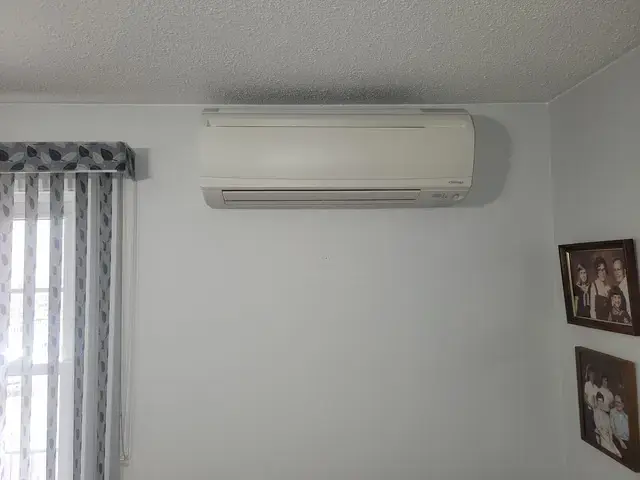 A technician is installing an air conditioning unit into a wall, with a focus on safety and efficiency, showcasing the importance of regular maintenance in hom…