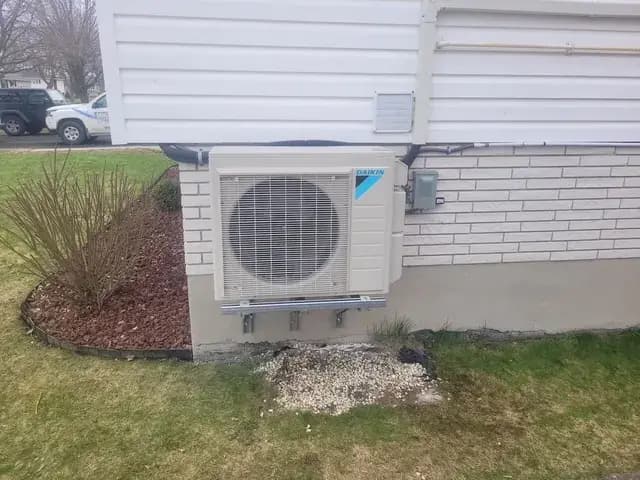 Outdoor heat pump unit with a large fan and Daikin logo, installed on the exterior wall of a