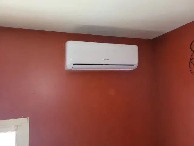 Air conditioning unit installed on a red wall