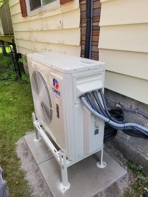 A new Gree heat pump is installed outside a house, with a large fan visible on the front