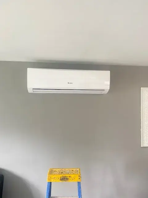Air conditioning unit mounted on wall with ladder in front