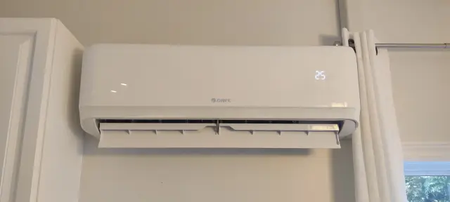 A white, wall-mounted Gree heat pump with a digital display showing temperature