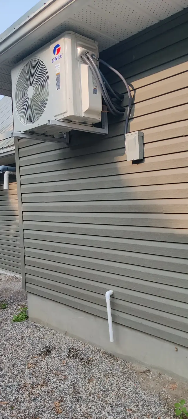 A close-up of the outdoor Gree heat pump unit, which is white and has a large fan. It