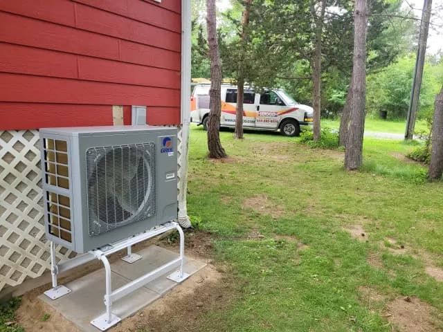 A new outdoor Gree heat pump is installed on the side of a house, with a red exterior