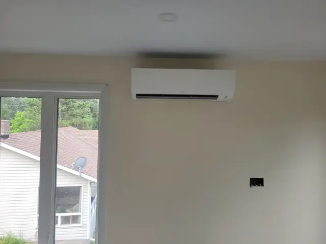 Air conditioning unit with a white casing is mounted on a beige wall