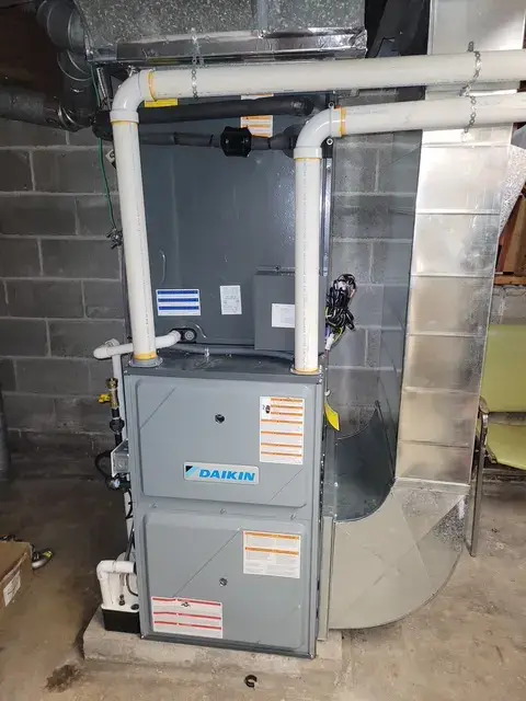 A Daikin furnace is installed in a basement with ductwork and piping around it