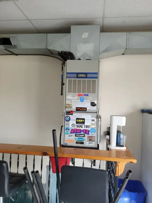 Outdoor Gree heat pump with a white casing and blue logo, installed on a concrete surface with a