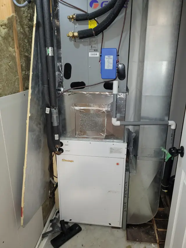 Outdoor Gree heat pump, newly installed. The pump is silver with blue and red logos and is connected