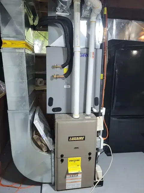 A Luxaire furnace is installed in a home, with visible piping and electrical connections