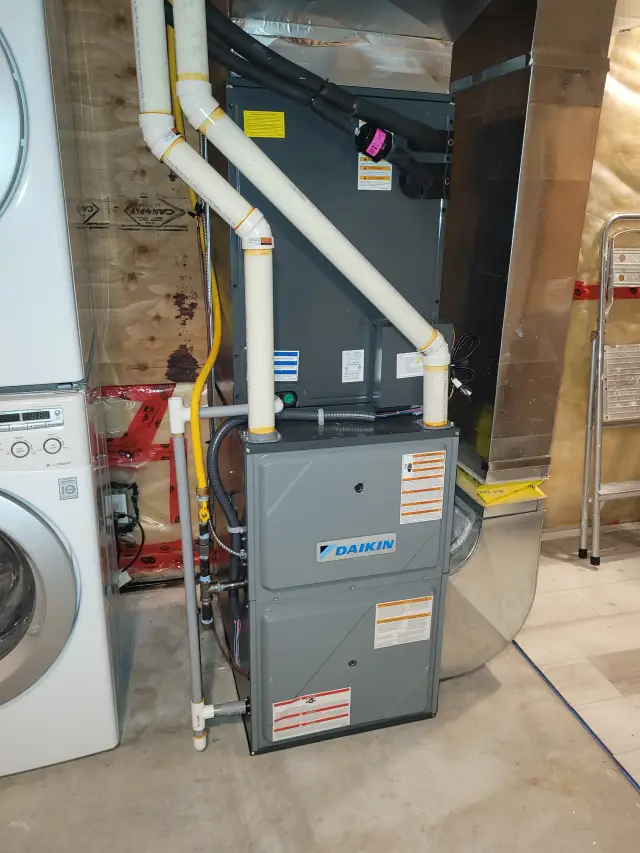 A Daikin furnace is installed in a laundry room with a washing machine to the left and a