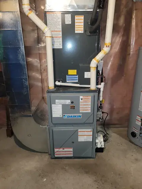 A Daikin furnace is installed in a basement setting with various pipes and ductwork around it