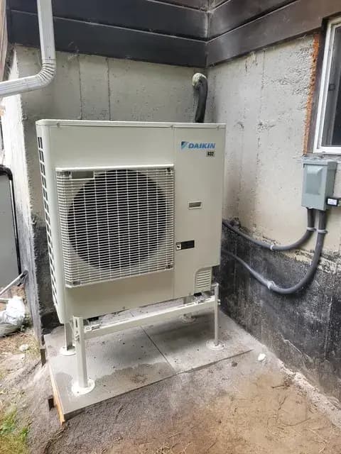 Outdoor heat pump unit with Daikin logo, installed on concrete slab