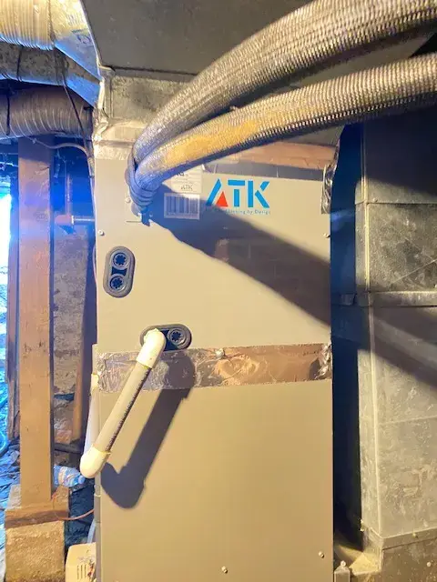 A close-up view of an ATK unit with flexible ducting installed, showing the brand logo and the metal