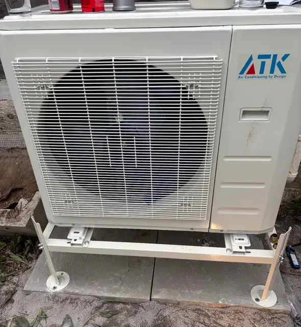 Outdoor Gree heat pump with a large fan and a white casing, installed on a concrete platform with