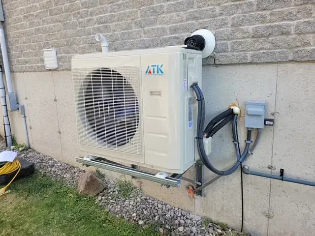 Outdoor Gree heat pump with large fan and venting system installed on the side of a house