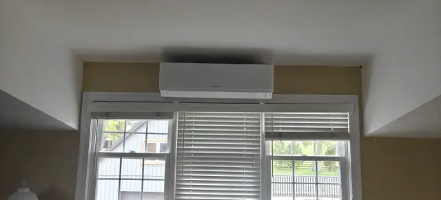 A window with closed horizontal blinds is visible in the image. The blinds are white and evenly spaced.