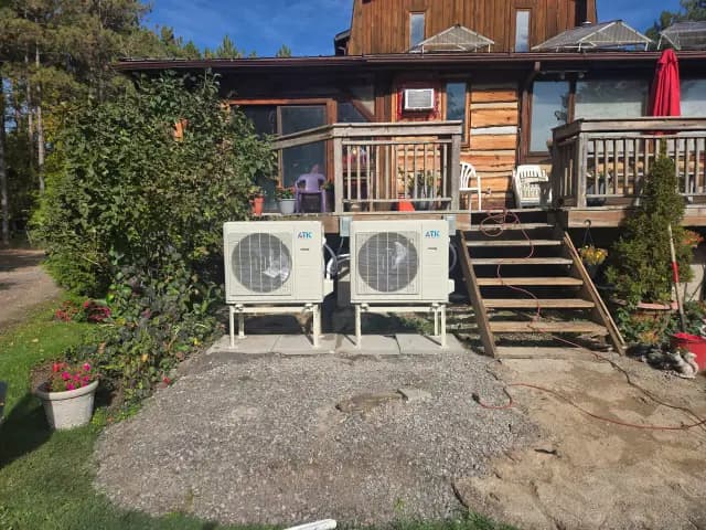 A newly installed outdoor Gree heat pump with a white casing and blue logo is placed on a