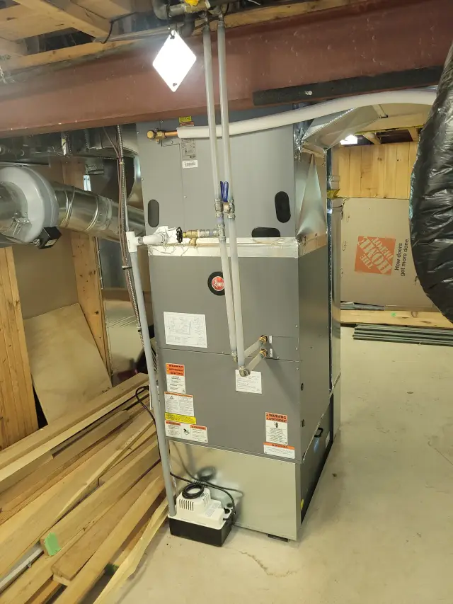 Outdoor Gree heat pump with a white casing and a red logo, installed on a wooden platform with