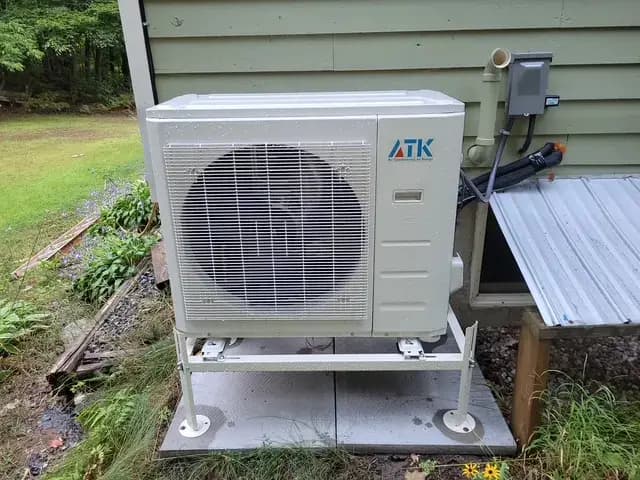 A new outdoor heat pump unit from the Gree brand is installed on a concrete platform outside a