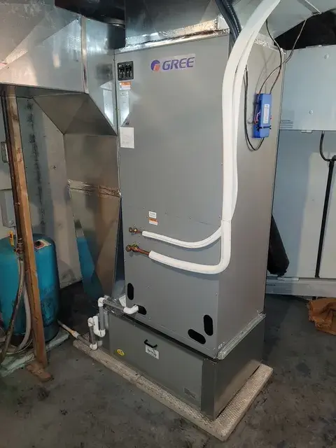 Outdoor Gree heat pump installed on concrete foundation with surrounding infrastructure