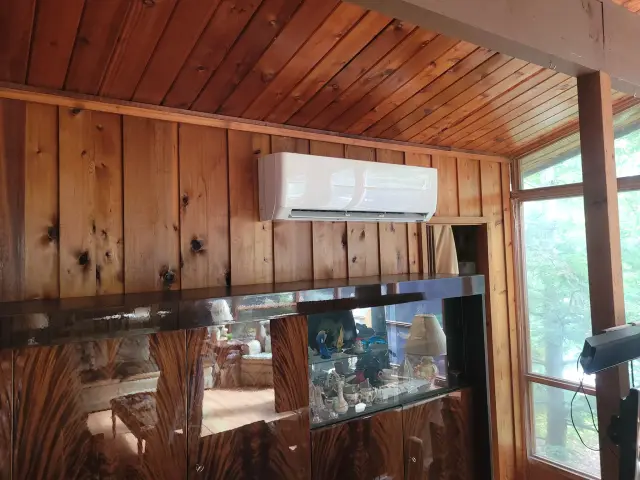 Air conditioning unit with a sleek design is mounted on a wooden wall