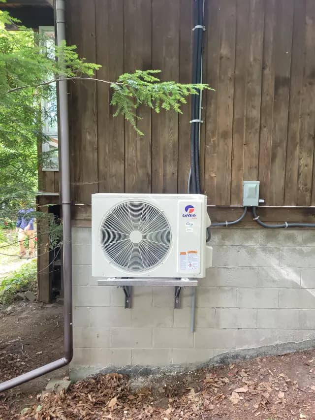 A new outdoor Gree heat pump is installed on the side of a house, with a large fan