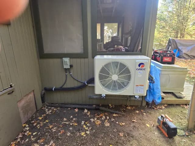 A new Gree heat pump is installed outside a house, with a large fan visible and a blue