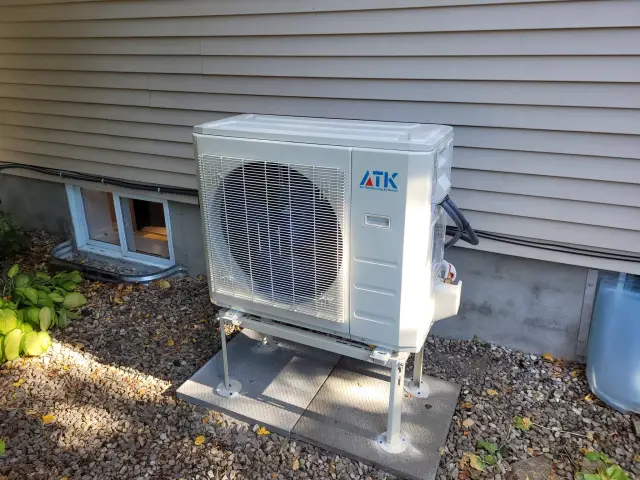 A newly installed outdoor Gree heat pump with a large fan and a white casing. It's placed on