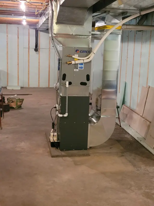 Outdoor heating unit with Gree branding, installed on a concrete pad