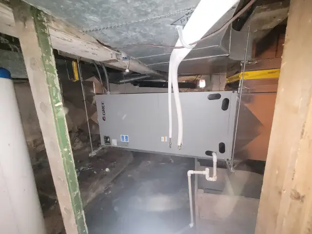 A new outdoor heat pump unit by Gree is installed in a residential setting. It's a large gray