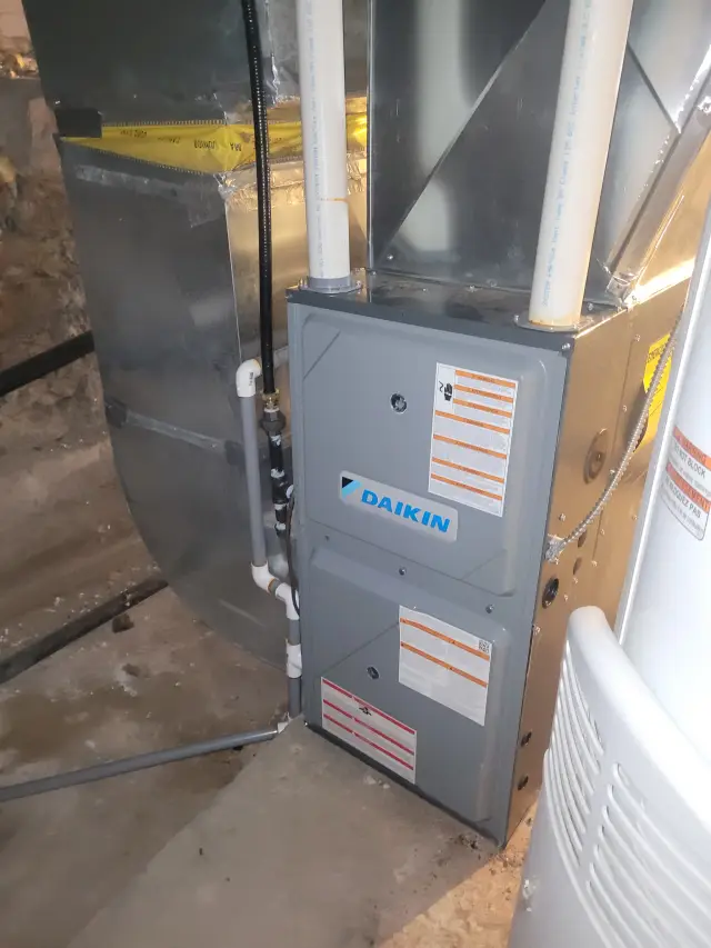 A Daikin furnace with its control panel and piping installed in a home's utility area