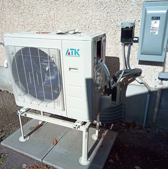 A new outdoor heat pump by Gree is installed on a platform outside a building. The unit is