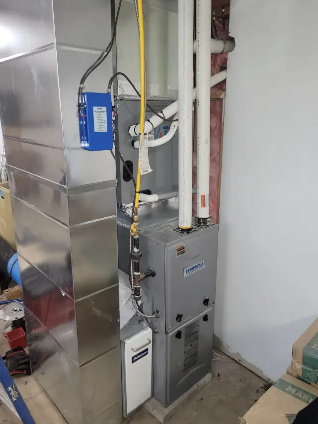 Outdoor Gree heat pump with a silver casing and a blue label, installed on a concrete surface with