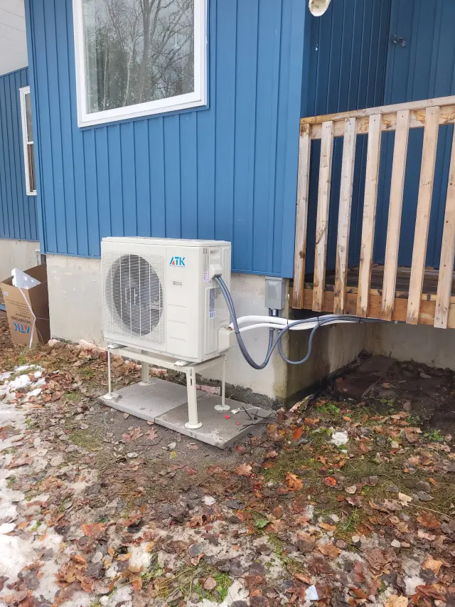 Outdoor heat pump unit with Gree logo installed outside a blue house