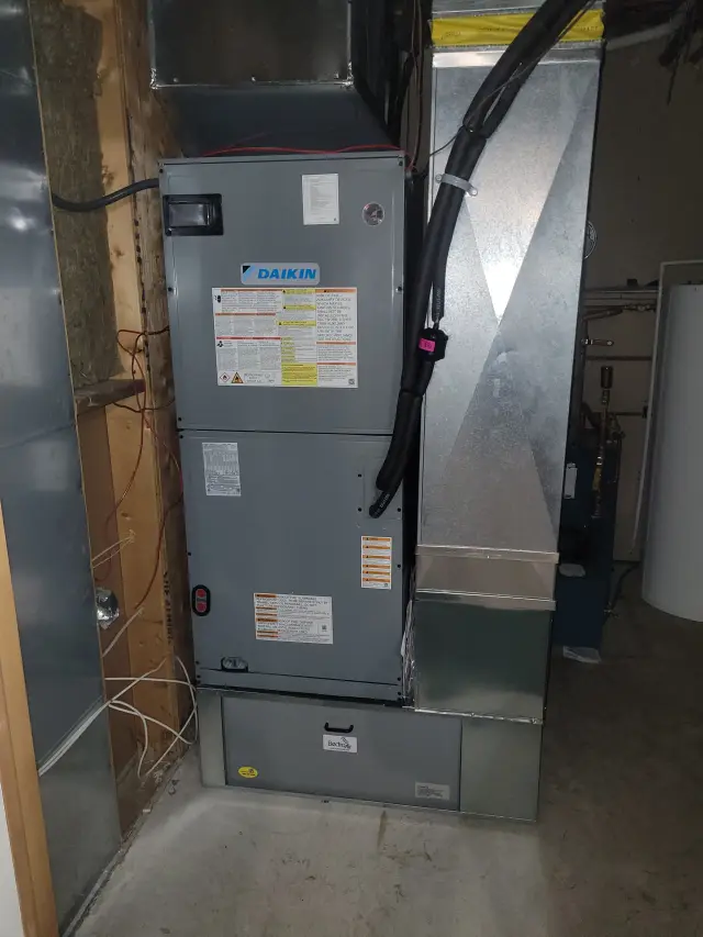 A Daikin furnace with various labels and instructions is installed in a room with wooden walls and a