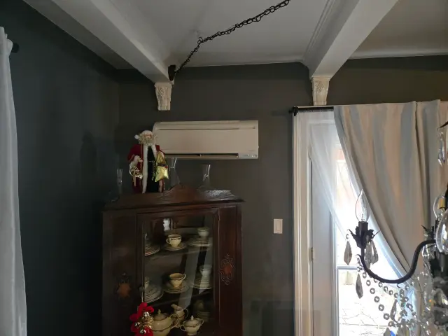 Air conditioning unit with a Santa figure on top of a wooden cabinet with dishes inside